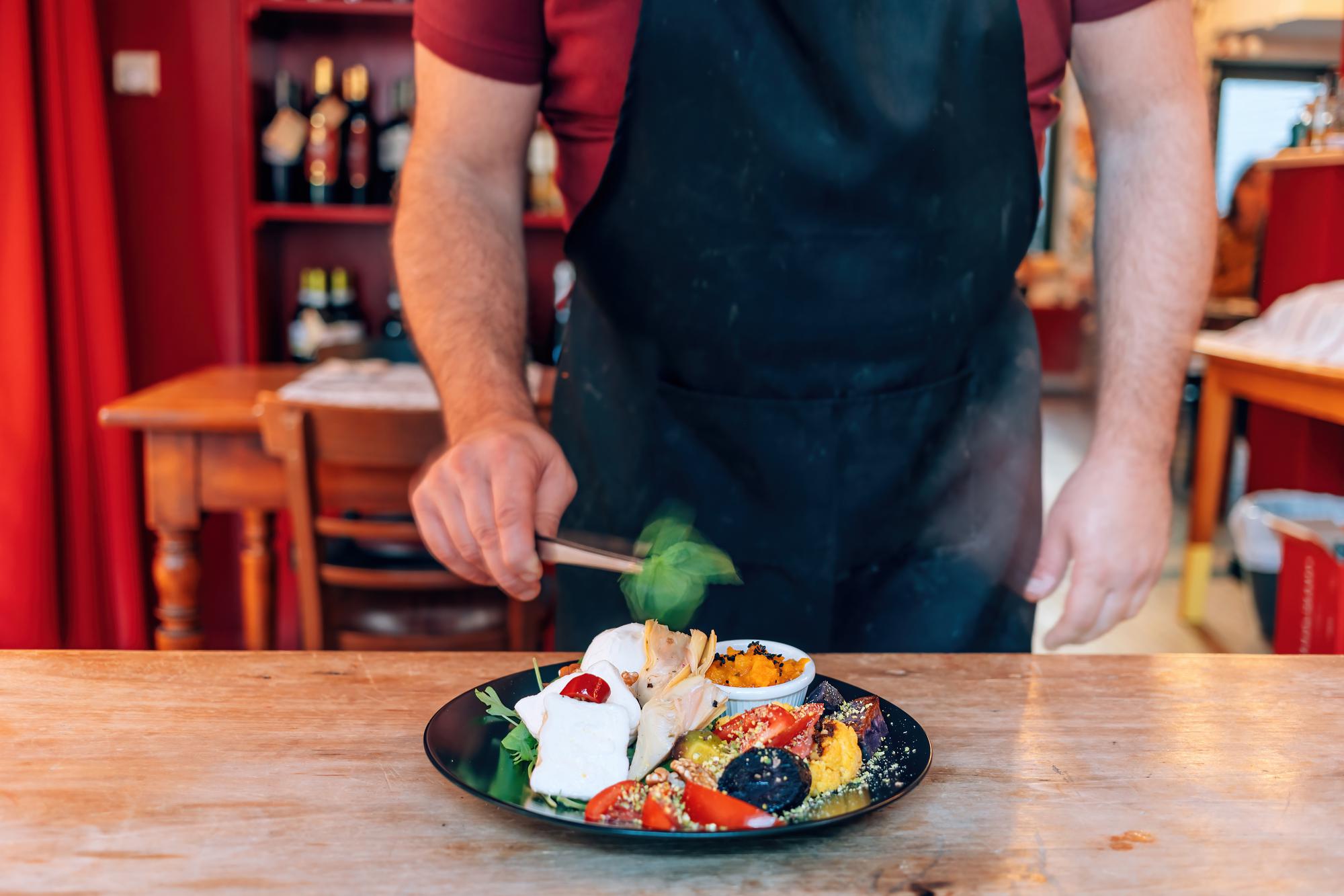 Chef arranging a plated dish on wooden table
